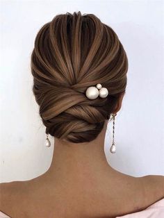 a woman with her hair in a low bun and pearls on the back of her head