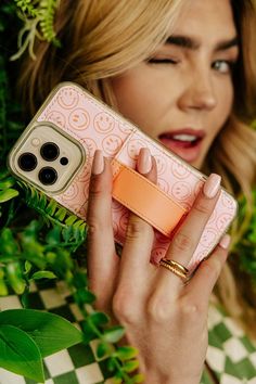 a woman holding a cell phone in her hand while wearing an orange and pink case