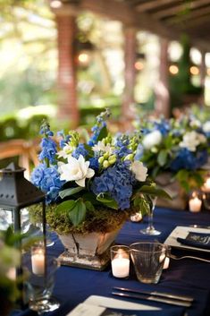 blue and white centerpieces with candles are on the table at this outdoor wedding