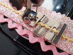 someone is using sewing machine to sew fabric on pink and white lace with yellow trim