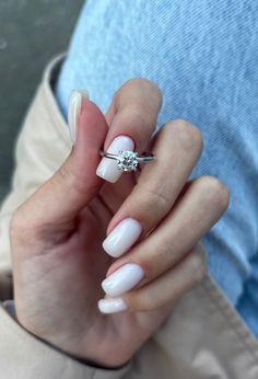 a woman's hand with white manies and a diamond ring on her finger