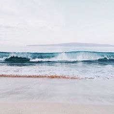 an ocean view with waves crashing on the beach