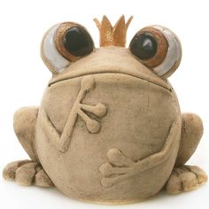 a ceramic frog with big eyes and a crown on its head, sitting down in front of a white background