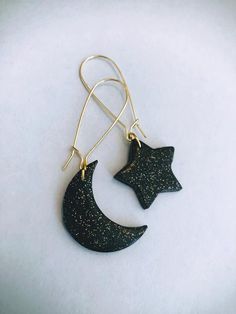 a pair of earrings with black stars hanging from it's earwires on a white surface