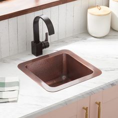 a copper sink in a kitchen with marble counter tops