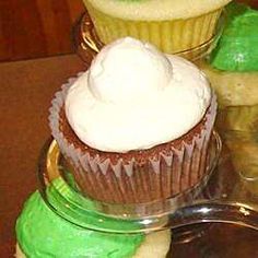 three cupcakes with white frosting and green icing sitting on top of each other