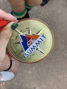 a person holding up a gold coin with the word summit on it's side