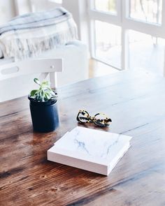 a wooden table topped with a book and sunglasses