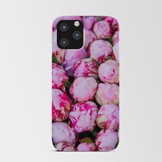 a bunch of pink flowers sitting on top of a white phone case next to each other