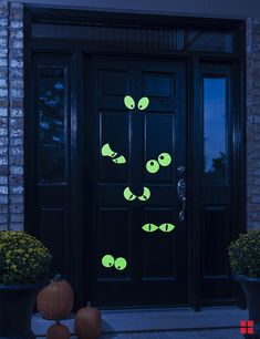 a black door with glow green fish on it and pumpkins in the foreground