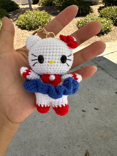 a hand holding a hello kitty keychain in it's palm