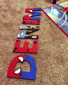 the name spiderman spelled out on the floor in front of a poster with other letters