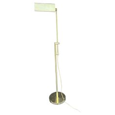 a floor lamp with a white light on it's side and a sign attached to the base