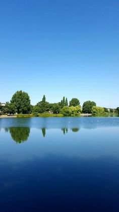 the blue water is reflecting trees in the distance