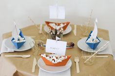 a table topped with plates and cups filled with food covered in marshmallows