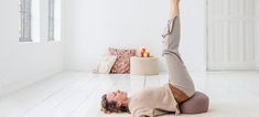 a woman is doing a yoga pose on the floor in front of a white wall