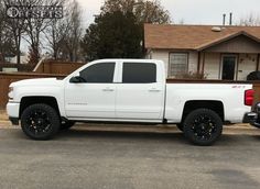 a white truck parked in front of a house with black wheels on it's tires