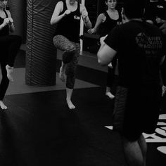 a group of people standing around each other in front of a punching bag on a gym floor