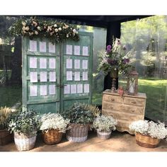 several baskets with flowers are sitting in front of an old door and some other plants