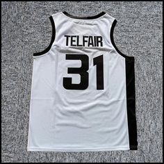 a white jersey with the number 31 on it is laying on top of a gray carpet