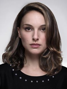 a woman with long brown hair is looking at the camera