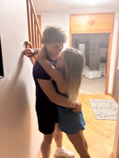 a man and woman hug in the middle of a room with wood flooring on either side of them