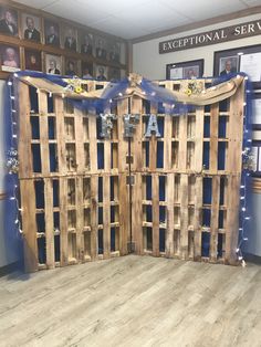 a room with wooden pallets and blue ribbon on the wall, decorated with pictures