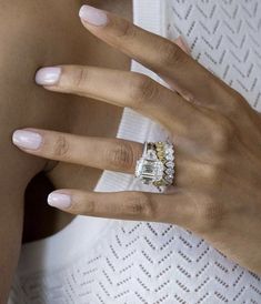 a woman's hand with a ring on her finger and an engagement ring in the other hand