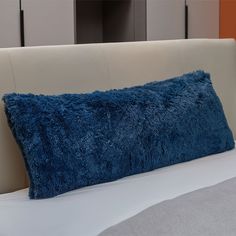 a blue pillow sitting on top of a white bed