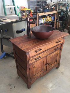 a bowl on top of a wooden cabinet in a garage with tools and other items