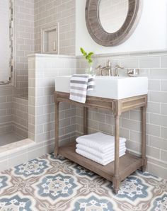 a white sink sitting under a mirror next to a bath tub in a room with tile flooring