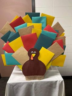 a turkey made out of paper sitting on top of a white tablecloth covered table