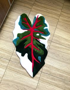 a green and red leaf rug on the floor