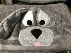 a gray dog towel with eyes and nose on it's back pocket, sitting on a table