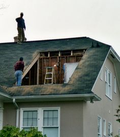 two men working on the roof of a house