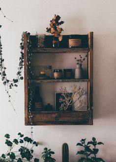 two wooden shelves with jars and candles on them next to some flowers in vases