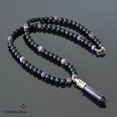 The centerpiece of this long gemstone men's necklace is an Amethyst healing point pendant. The combination of black matte onyx and shiny purple striped amethyst beads creates balanced, manly and sophisticated look. This piece is perfect for making a statement effortlessly and stylishly. This necklace is strung on a beaded wire and finished off with a lobster claw clasp. You can select the necklace length from the drop-down menu on the right. The pendant measures approximately 2.36 inches long (6 Mens Beaded Necklaces, Tigers Eye Necklace, Amethyst Healing, Healing Crystal Jewelry, Jewelry For Men, Necklace For Men, Amethyst Beads, Necklace Long, Necklace Black