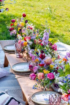 a long table with plates and vases filled with colorful flowers on top of it