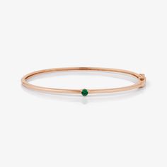 A timeless gold bangle showcases a solitary emerald at its center, infusing elegance with a touch of brilliance. Yellow Gold Bracelets For May Birthstone, Formal Yellow Gold Bracelet With May Birthstone, Formal Yellow Gold Bracelets For May Birthstone, 14k Gold Bracelet For Formal Occasions With May Birthstone, Formal 14k Gold Bracelet With May Birthstone, Classic Bracelets With May Birthstone, Classic Emerald Bracelets For Formal Occasions, Luxury Solitaire Jewelry For May Birthstone, Fine Jewelry Green Bangle For Anniversary