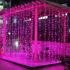 a gazebo covered in pink lights on the side of a building