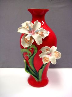 a red vase with flowers painted on it