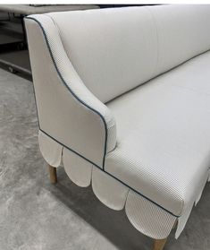 a white couch with blue piping on the arm and back, sitting in a room