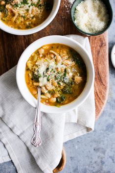 two bowls filled with soup on top of a wooden cutting board next to silverware