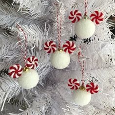 three ornaments hanging from a white christmas tree with candy canes on it's sides