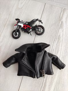 a toy motorcycle is next to a black leather jacket on the floor with a red and white motorbike