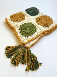 a crocheted square with tassels is shown on a white table top