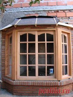 a corner window on the side of a brick building with a tiled roof and glass panes