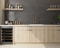 a kitchen filled with lots of bottles and wine glasses on top of the counter next to a sink