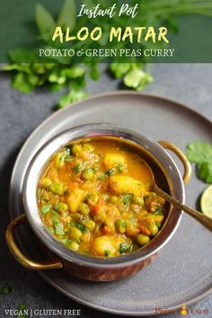 a bowl filled with potato and green peas curry on top of a metal plate next to cilantro