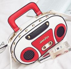 a white and red handbag sitting on top of a bed next to an mp3 player